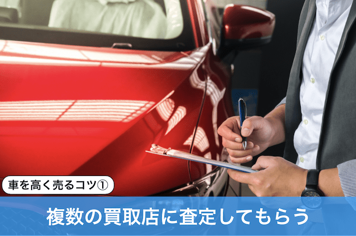 赤い車を査定する男