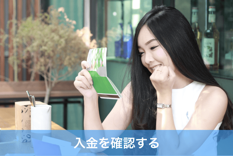 通帳をみてガッツポーズする女性